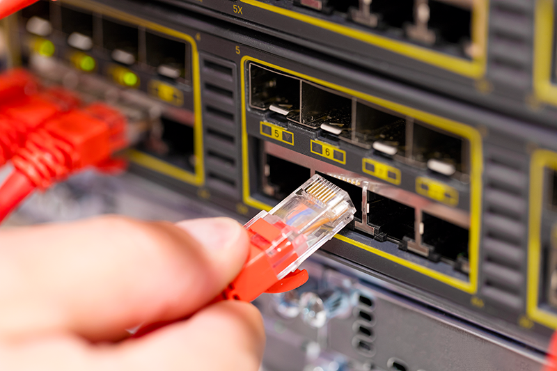 network engineer connects a network cable to a switch