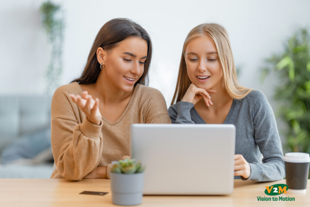 Two happy young women using laptop. Friends spending time together.